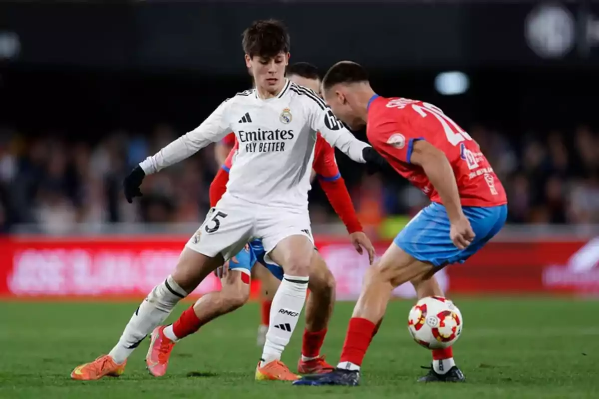 Dos jugadores de fútbol compiten por el balón en un partido.