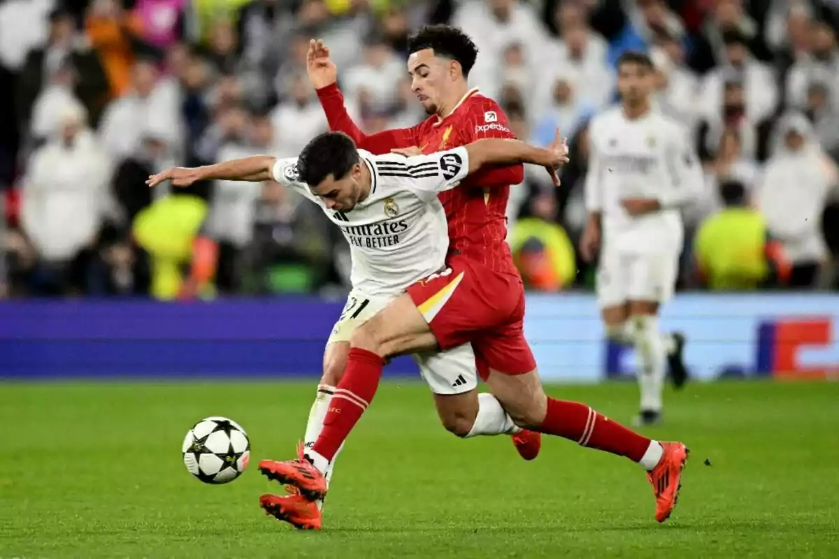 Two soccer players compete for the ball in a match, one in a white uniform and the other in a red uniform, in a stadium full of spectators. Two soccer players compete for the ball in a match, one in a white uniform and the other in a red uniform, in a stadium full of spectators.