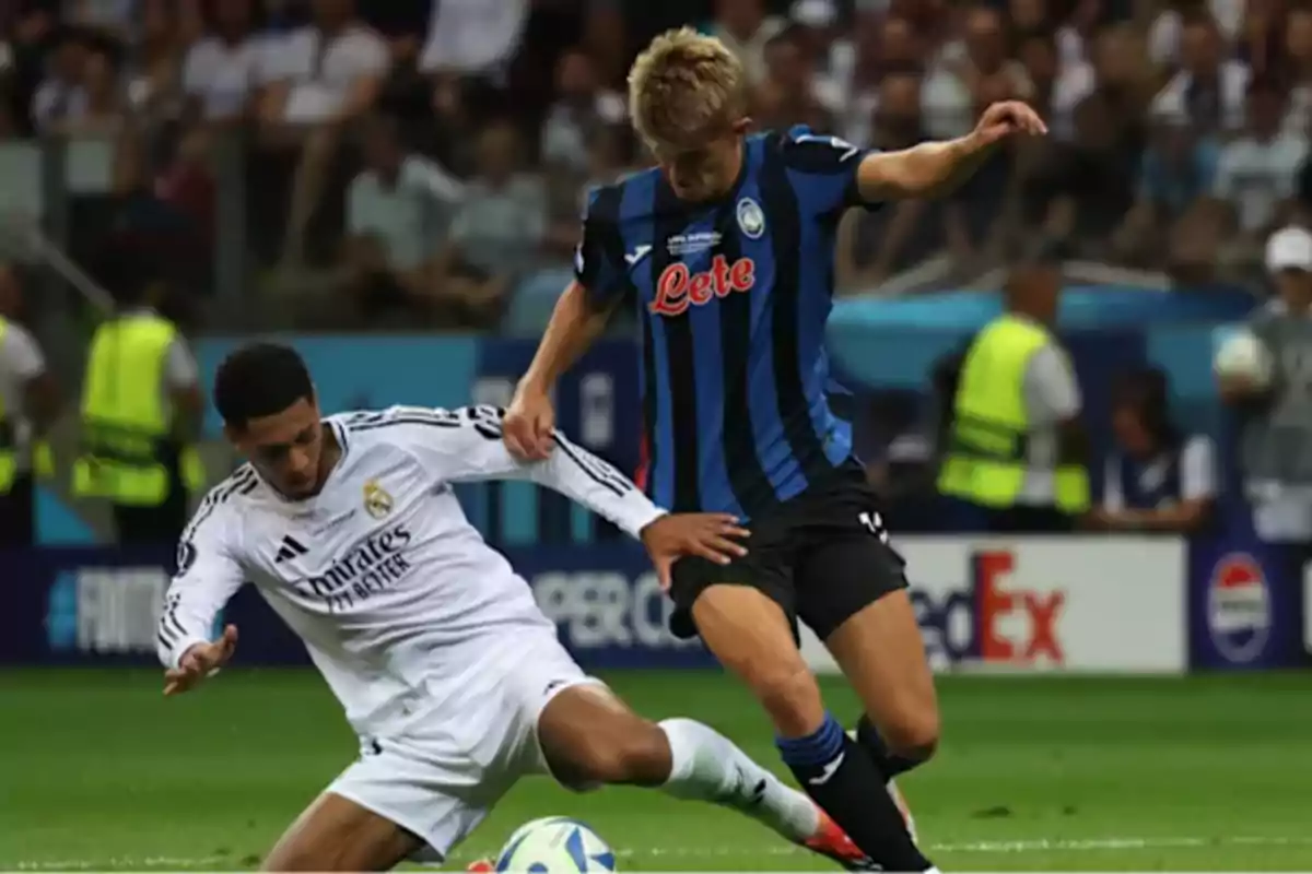 Two soccer players compete for the ball in a game, one wearing a white uniform and the other wearing a blue and black uniform.