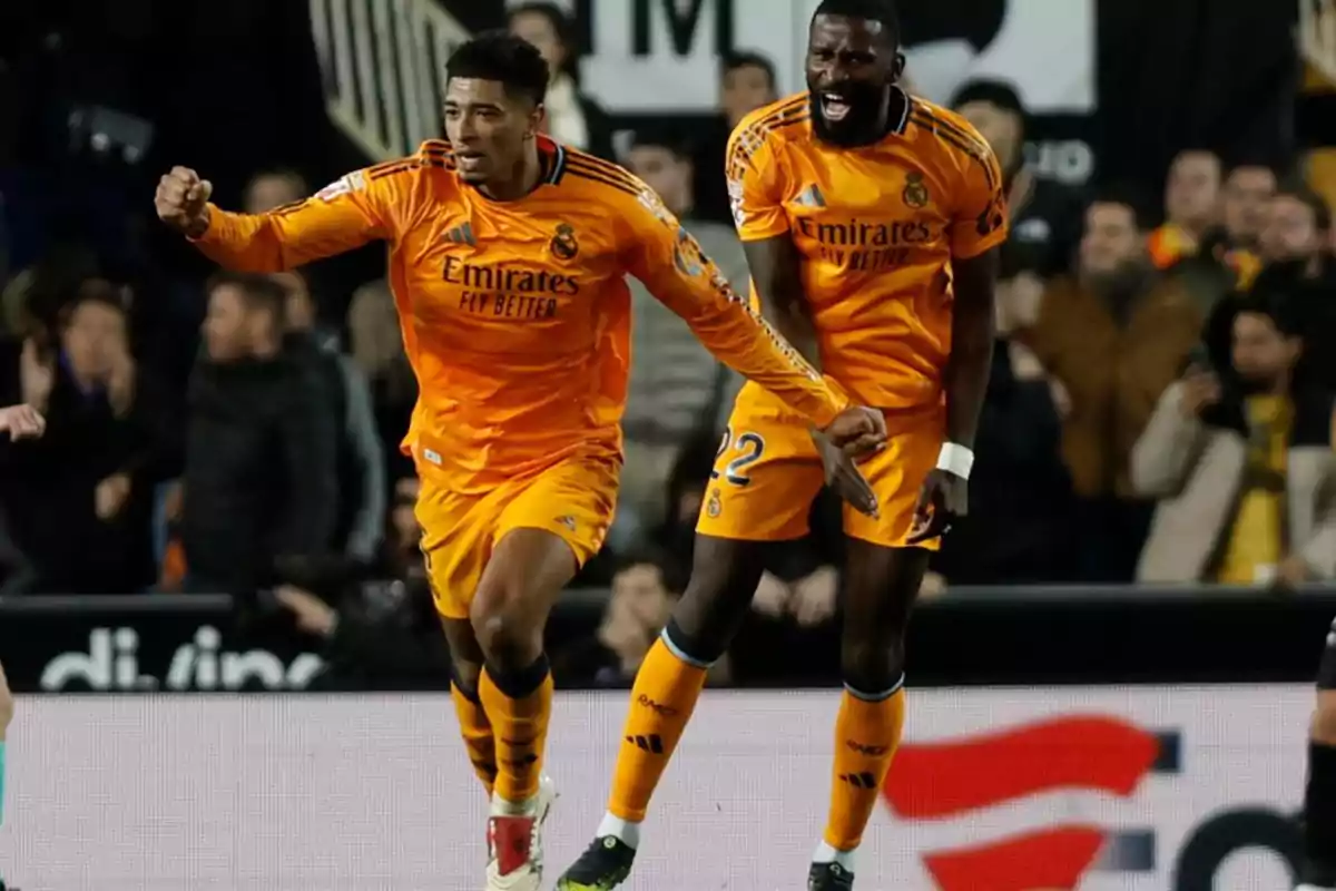 Real Madrid soccer players celebrating a goal during a match, wearing orange uniforms. Real Madrid soccer players celebrating a goal during a match, wearing orange uniforms.