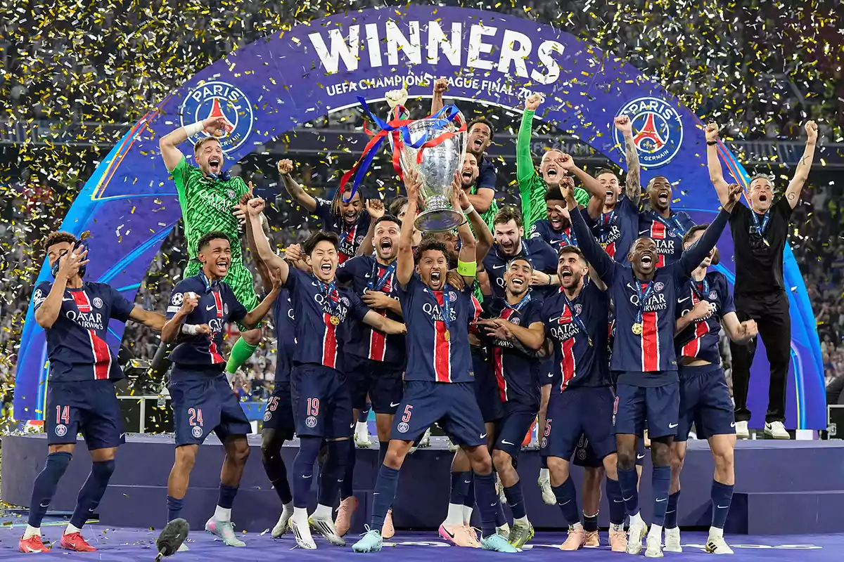 Jugadores del PSG celebran eufóricos levantando el trofeo de la Champions League rodeados de confeti dorado bajo un arco que dice WINNERS Jugadores del PSG celebran eufóricos levantando el trofeo de la Champions League rodeados de confeti dorado bajo un arco que dice WINNERS