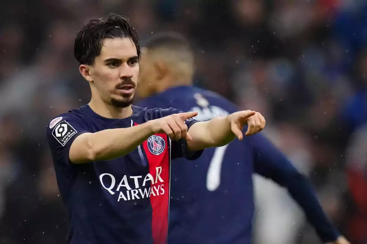 Futbolista del PSG con uniforme azul y rojo señalando con ambas manos durante un partido Futbolista del PSG con uniforme azul y rojo señalando con ambas manos durante un partido