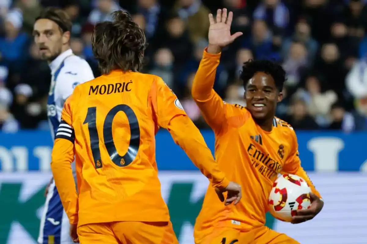 Soccer players in orange uniforms celebrate on the field during a match.