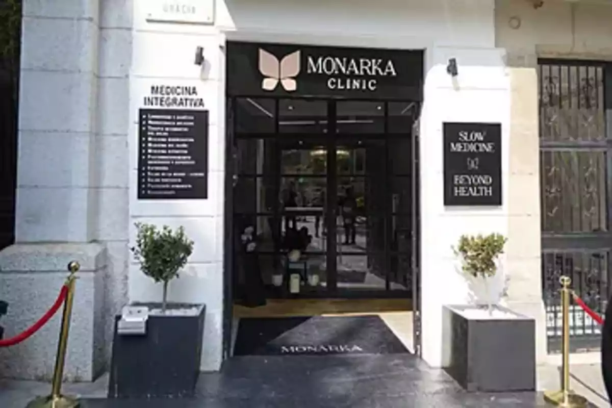 Main entrance of a clinic called Monarka Clinic with two large flowerpots on each side and informational signs on the facade Main entrance of a clinic called Monarka Clinic with two large flowerpots on each side and informational signs on the facade