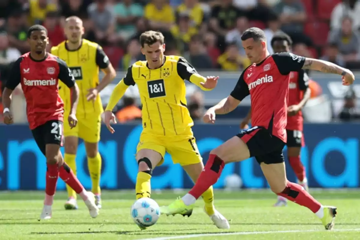 Players from two different soccer teams compete for the ball on the field during a match.