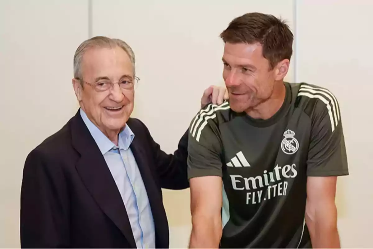 Dos hombres sonríen y posan juntos, uno lleva traje y el otro viste ropa deportiva del Real Madrid Dos hombres sonríen y posan juntos, uno lleva traje y el otro viste ropa deportiva del Real Madrid