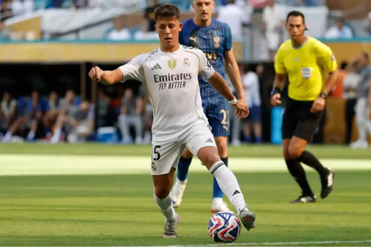 Real Madrid player controlling the ball during a match with an opposing player and a referee in the background Real Madrid player controlling the ball during a match with an opposing player and a referee in the background