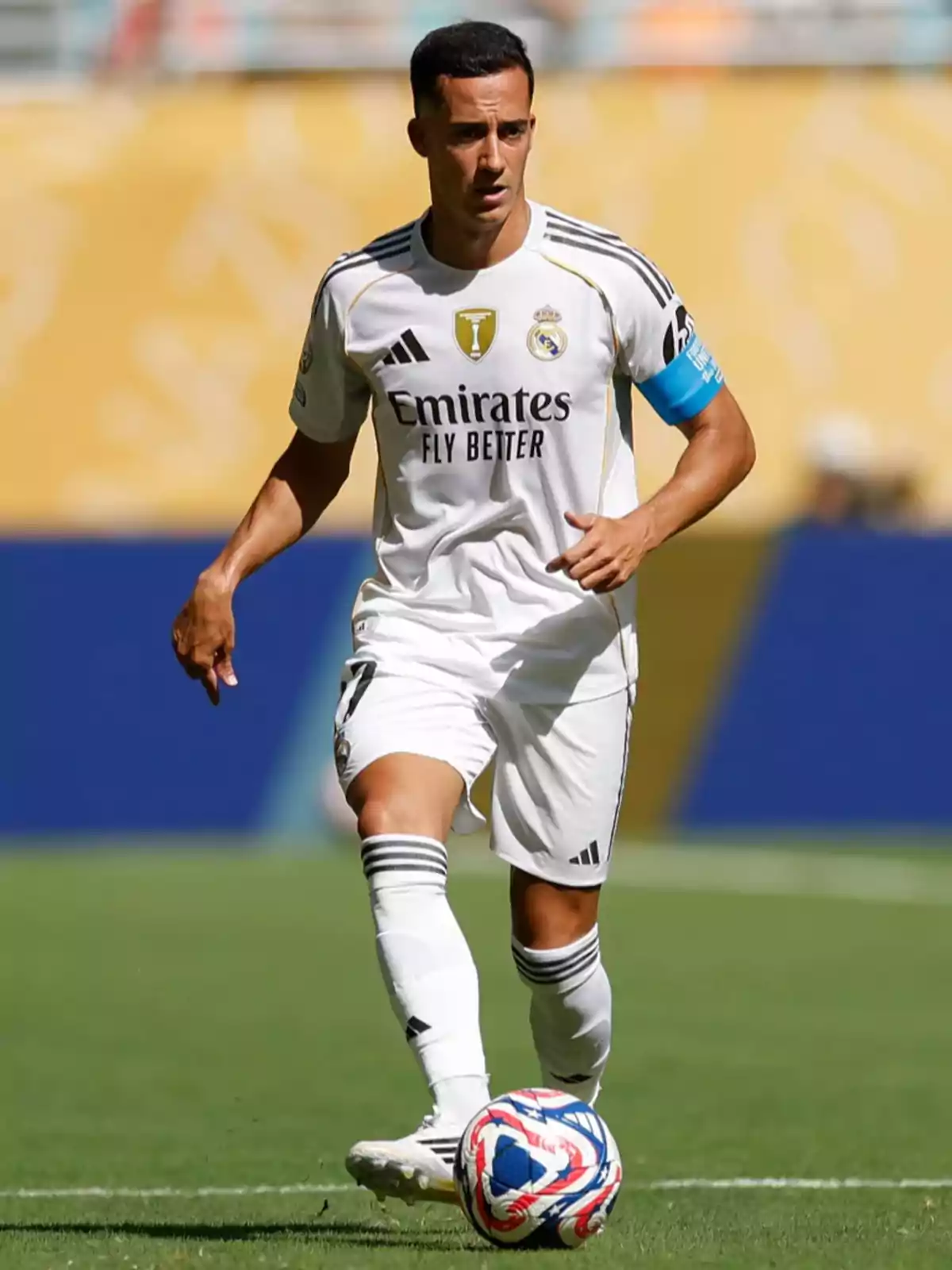 Real Madrid player in a white uniform controlling the ball during a match on grass Real Madrid player in a white uniform controlling the ball during a match on grass