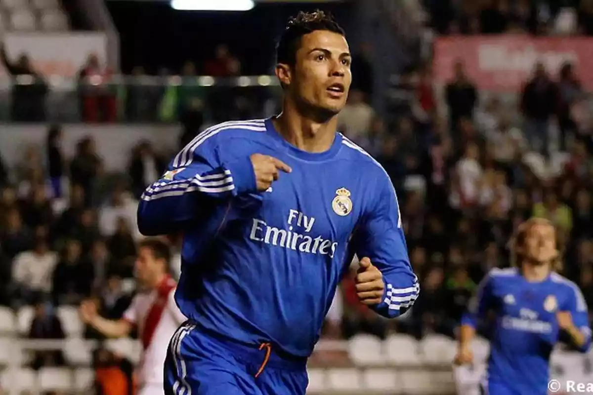 Soccer player in a blue Real Madrid uniform celebrating a goal in a stadium full of spectators Soccer player in a blue Real Madrid uniform celebrating a goal in a stadium full of spectators