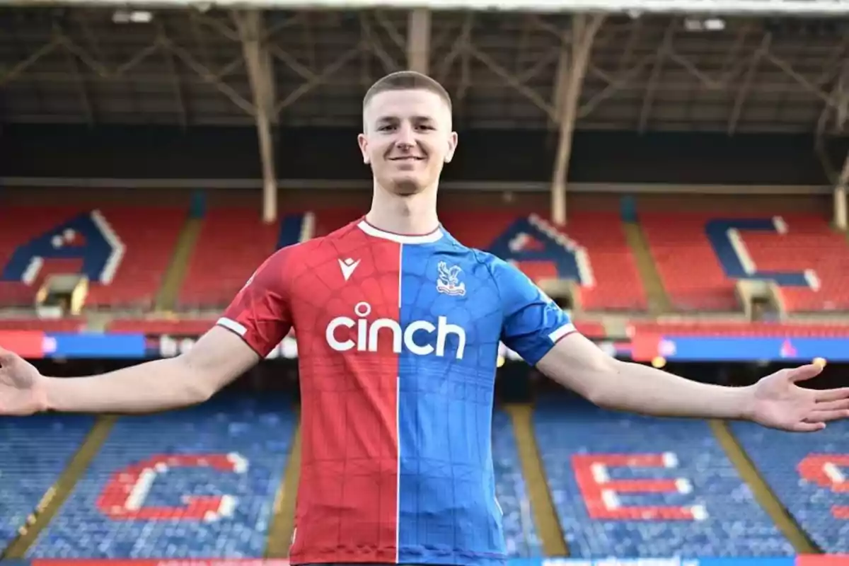 Jugador de fútbol con los brazos extendidos vistiendo el uniforme de Crystal Palace en un estadio vacío Jugador de fútbol con los brazos extendidos vistiendo el uniforme de Crystal Palace en un estadio vacío