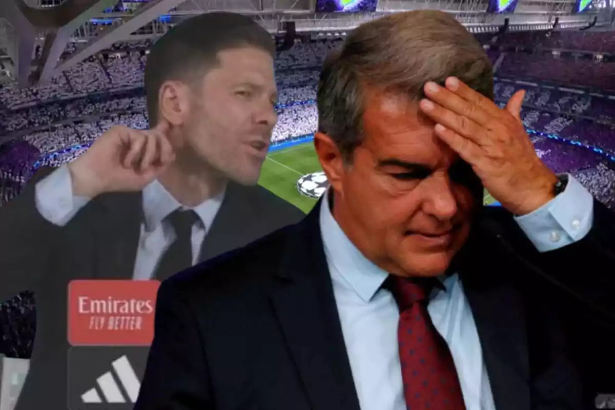 Two men in suits at a soccer stadium, one of them looking thoughtful and worried while the other makes a gesture with his hand near his neck.