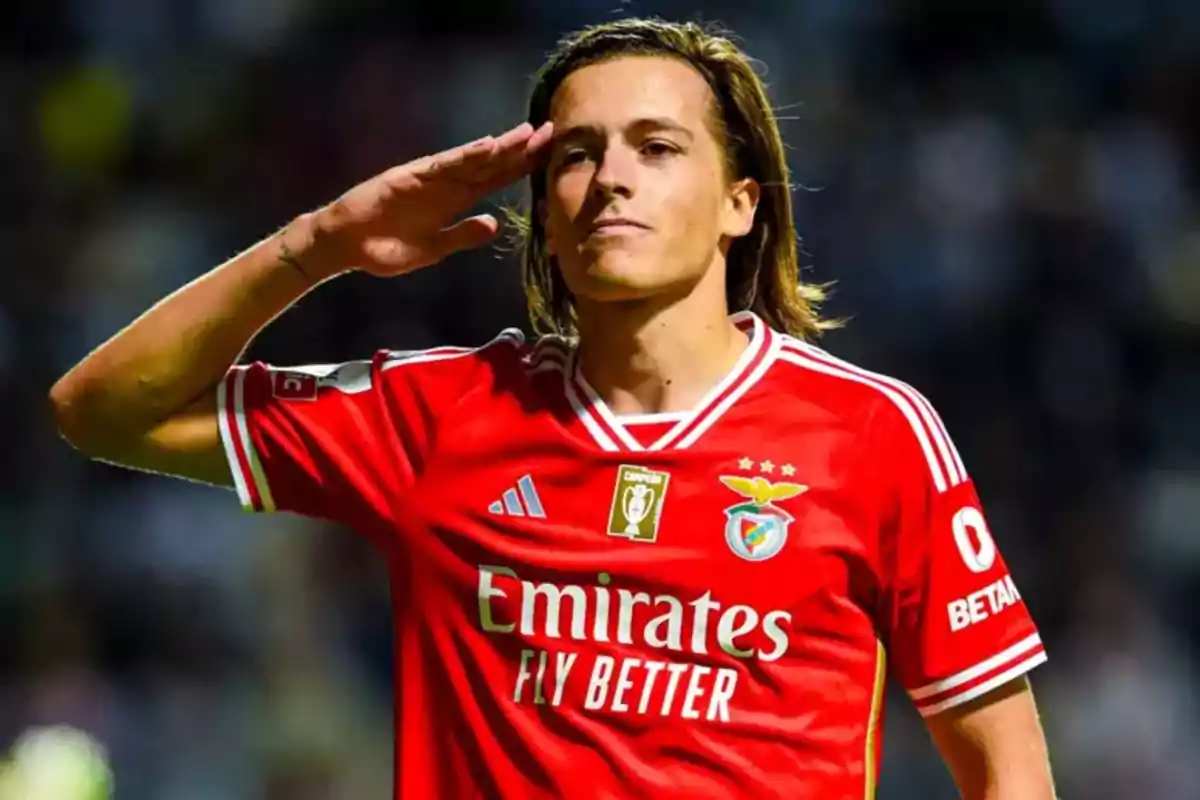 Futbolista con uniforme rojo del Benfica haciendo un saludo militar en el campo de juego