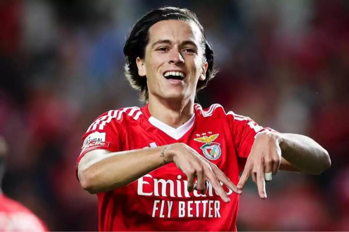 Futbolista con uniforme rojo del Benfica celebrando un gol con una sonrisa y haciendo un gesto con las manos Futbolista con uniforme rojo del Benfica celebrando un gol con una sonrisa y haciendo un gesto con las manos