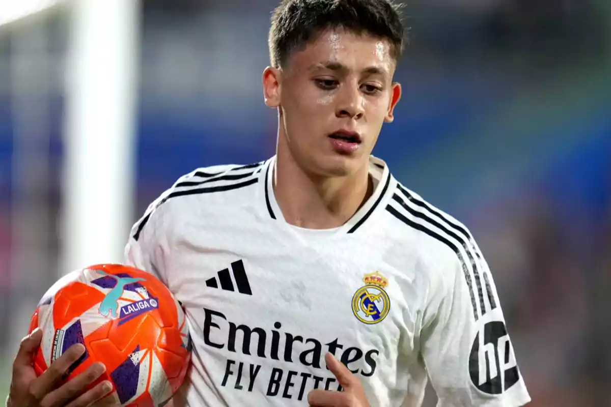 Jugador del Real Madrid con uniforme blanco sosteniendo un balón de fútbol durante un partido Jugador del Real Madrid con uniforme blanco sosteniendo un balón de fútbol durante un partido