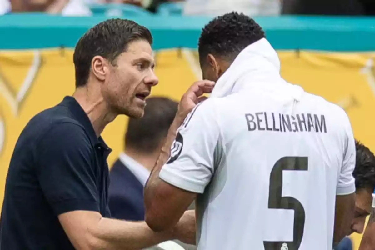Soccer coach giving instructions to a player wearing the number 5 jersey with the name Bellingham on the back during a match Soccer coach giving instructions to a player wearing the number 5 jersey with the name Bellingham on the back during a match