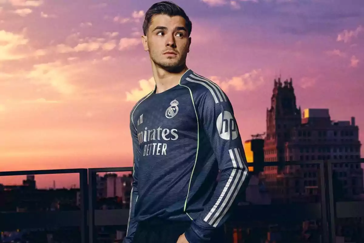 A player wearing the Real Madrid uniform poses on a terrace at sunset with buildings in the background. A player wearing the Real Madrid uniform poses on a terrace at sunset with buildings in the background.