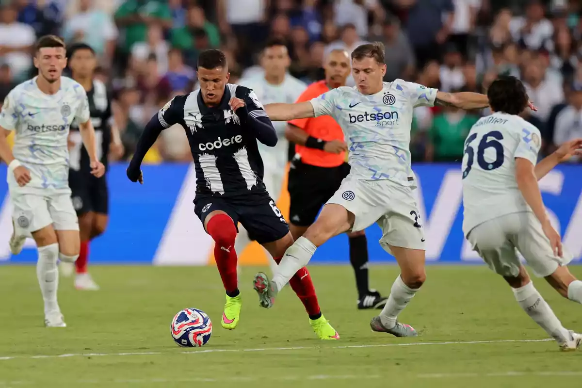 Jugadores de fútbol disputan el balón durante un partido en un estadio lleno de espectadores Jugadores de fútbol disputan el balón durante un partido en un estadio lleno de espectadores