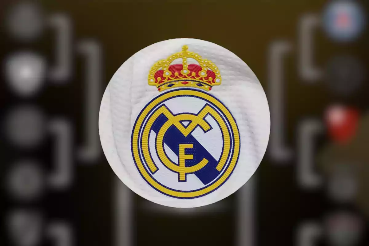 Escudo del Real Madrid sobre fondo desenfocado de un cuadro de torneo