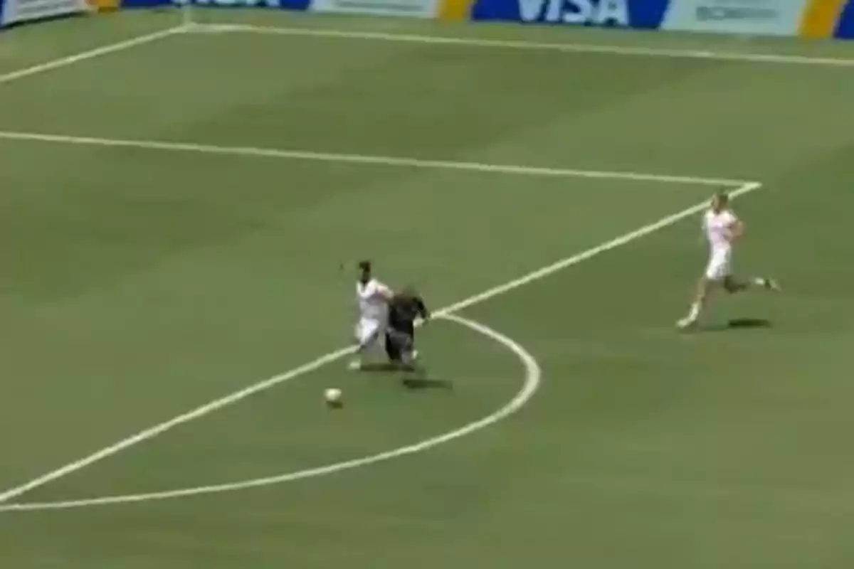 Una jugadora de fútbol es derribada por la portera fuera del área mientras otra jugadora corre hacia la jugada Una jugadora de fútbol es derribada por la portera fuera del área mientras otra jugadora corre hacia la jugada