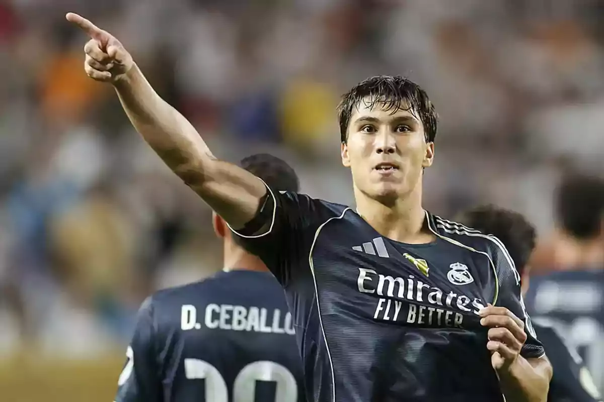 Futbolista del Real Madrid celebrando un gol mientras señala con el brazo extendido y sostiene la camiseta del equipo Futbolista del Real Madrid celebrando un gol mientras señala con el brazo extendido y sostiene la camiseta del equipo