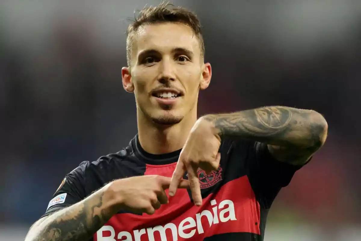 Soccer player wearing a black and red jersey celebrating a goal by making a hashtag gesture with his hands Soccer player wearing a black and red jersey celebrating a goal by making a hashtag gesture with his hands