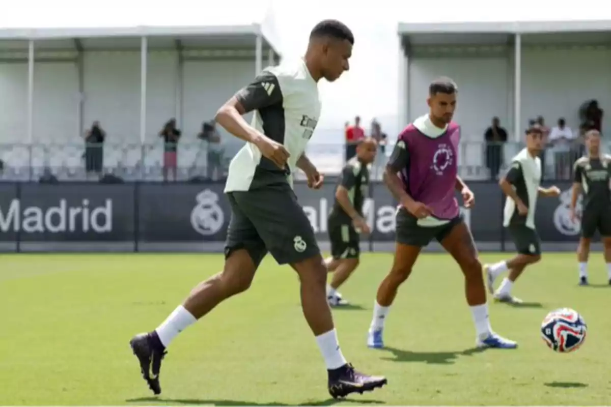 Jugadores de fútbol entrenando en un campo con uniforme del Real Madrid mientras practican con un balón