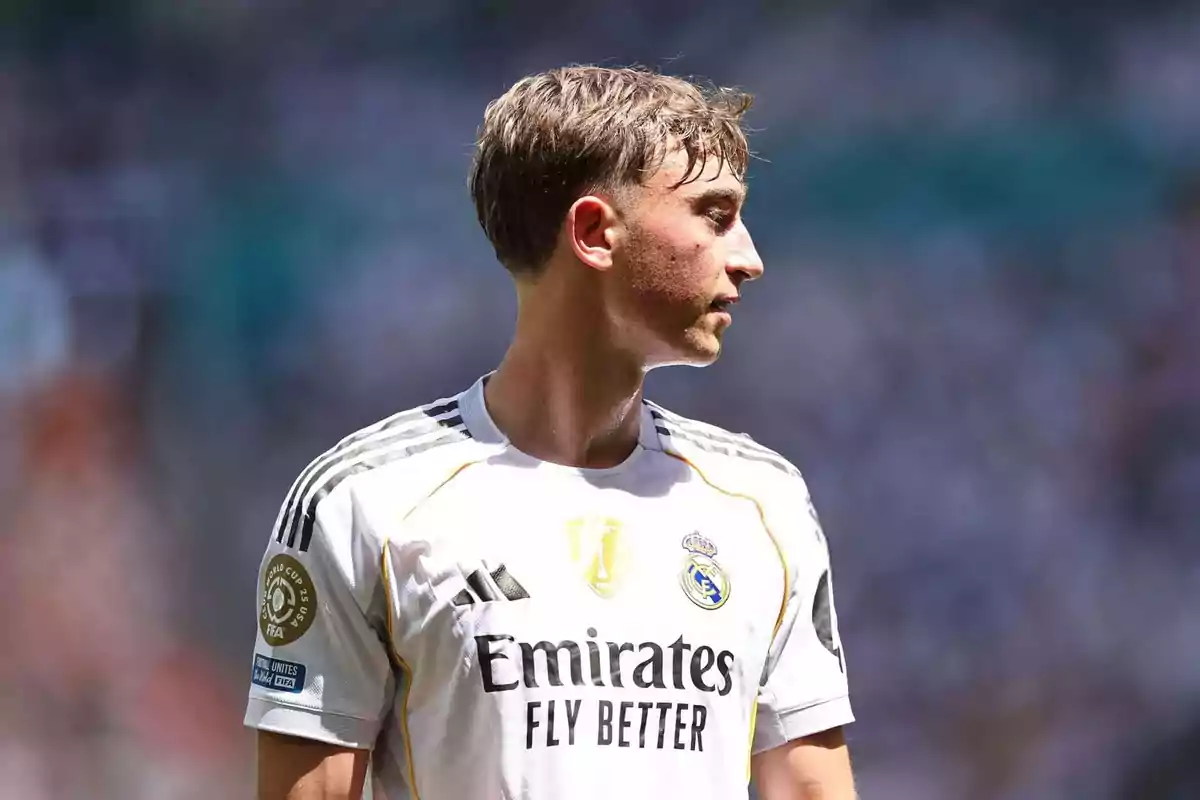 Jugador de fútbol con uniforme blanco del Real Madrid mirando hacia la derecha en un estadio iluminado por el sol Jugador de fútbol con uniforme blanco del Real Madrid mirando hacia la derecha en un estadio iluminado por el sol