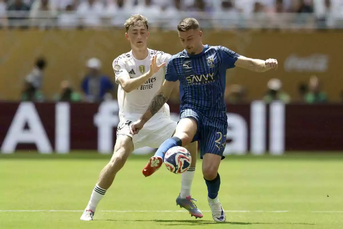 Dos futbolistas disputan el balón durante un partido en un estadio lleno de espectadores Dos futbolistas disputan el balón durante un partido en un estadio lleno de espectadores