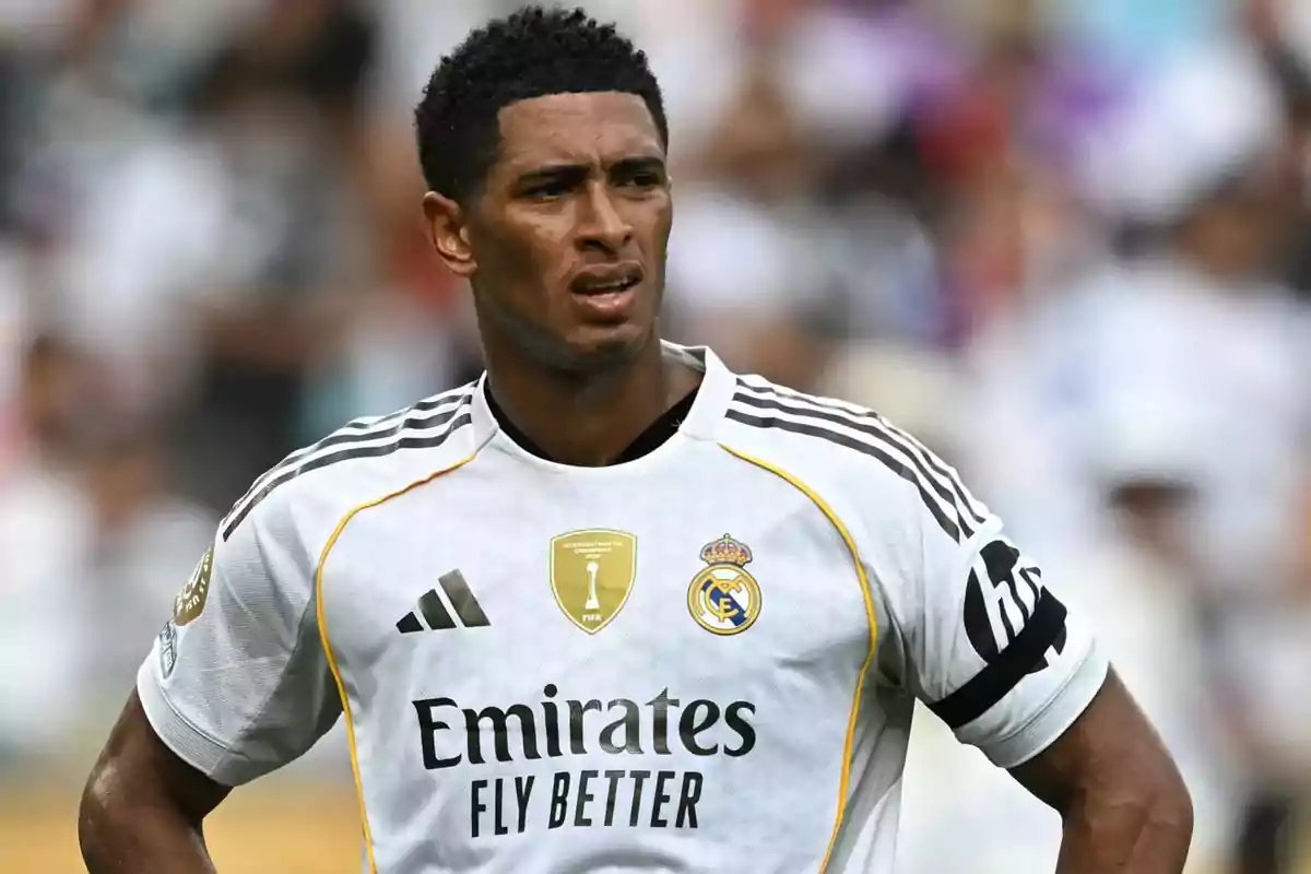 Real Madrid player with a serious expression during a match, wearing the team’s white uniform and a black armband on the left arm Real Madrid player with a serious expression during a match, wearing the team’s white uniform and a black armband on the left arm