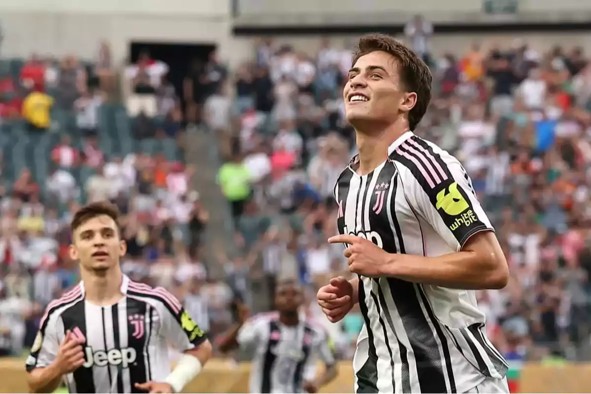 Dos futbolistas con uniforme de la Juventus celebran en la cancha durante un partido con público en las gradas. Dos futbolistas con uniforme de la Juventus celebran en la cancha durante un partido con público en las gradas.