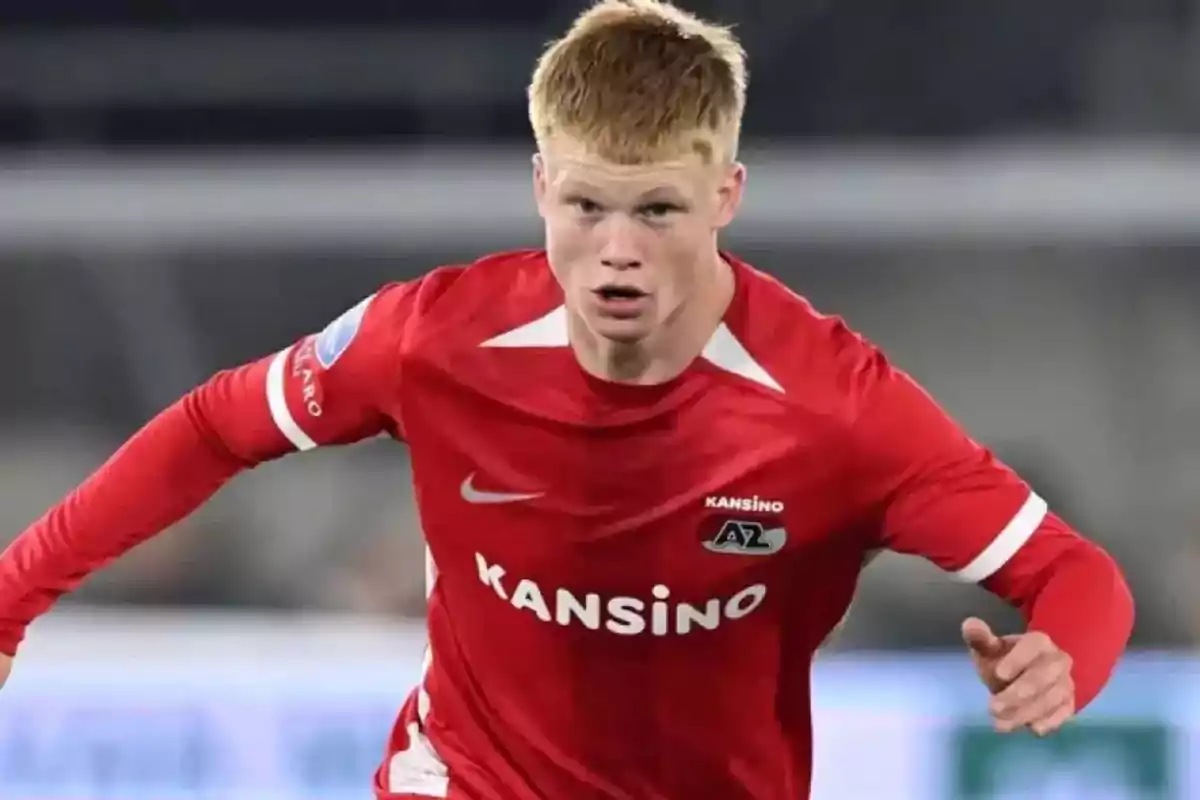 Jugador de fútbol con uniforme rojo del AZ Alkmaar corriendo en el campo durante un partido Jugador de fútbol con uniforme rojo del AZ Alkmaar corriendo en el campo durante un partido
