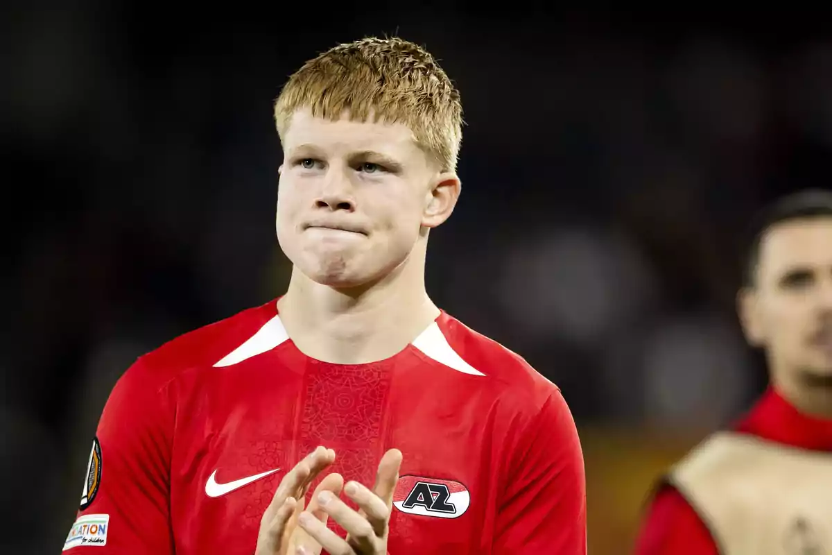 Soccer player wearing a red AZ Alkmaar jersey applauding on the field Soccer player wearing a red AZ Alkmaar jersey applauding on the field