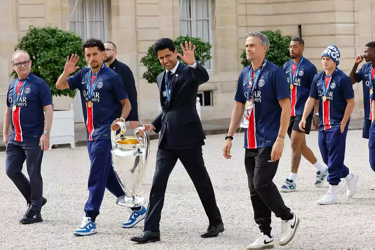 Jugadores y directivos del PSG caminan juntos celebrando con el trofeo de la Champions League, todos llevan medallas y visten camisetas del equipo. Jugadores y directivos del PSG caminan juntos celebrando con el trofeo de la Champions League, todos llevan medallas y visten camisetas del equipo.