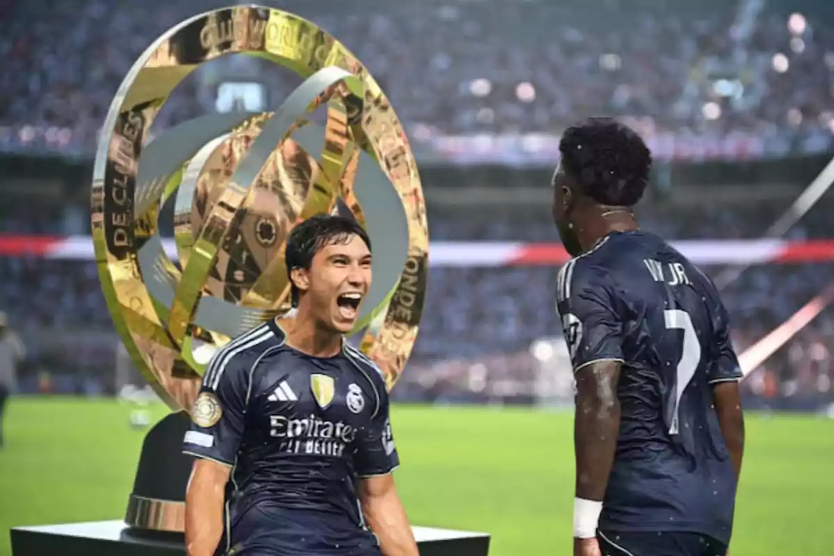Two Real Madrid players celebrate in front of a large golden trophy in a stadium full of fans.