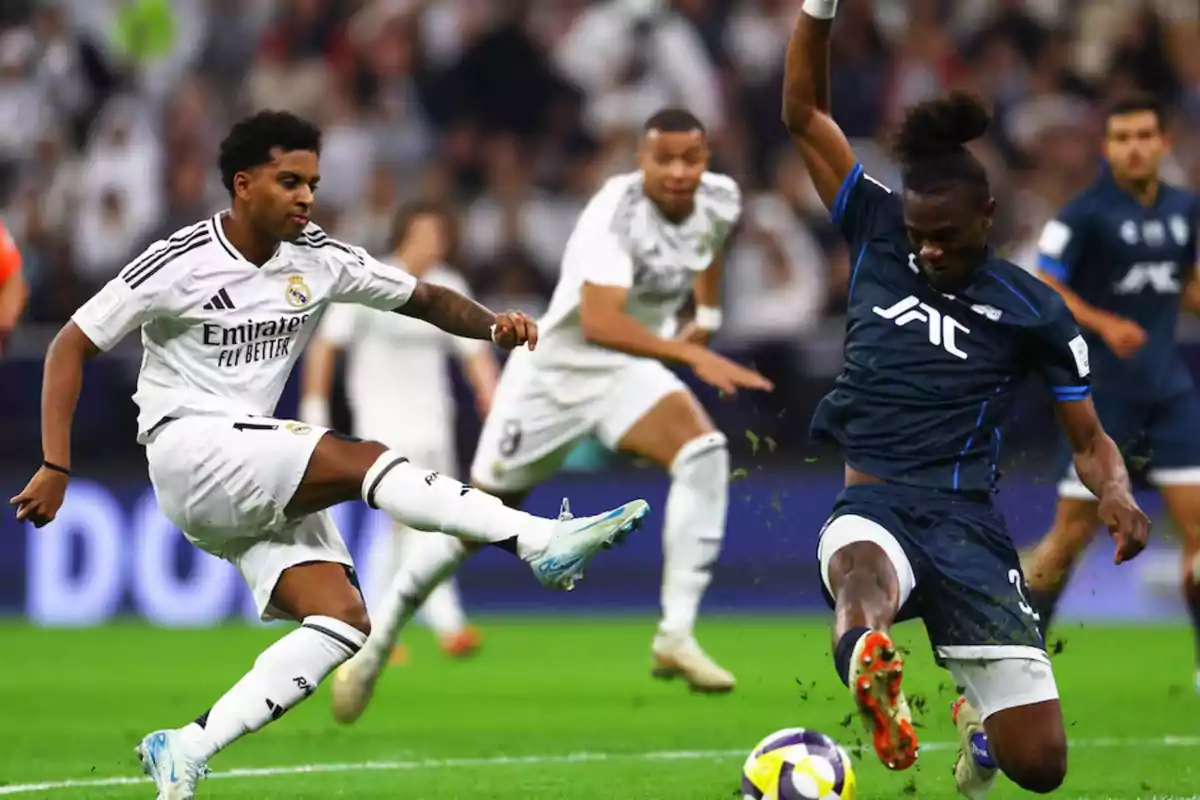 Two players fight for the ball during a match while other players watch the play in the background. Two players fight for the ball during a match while other players watch the play in the background.
