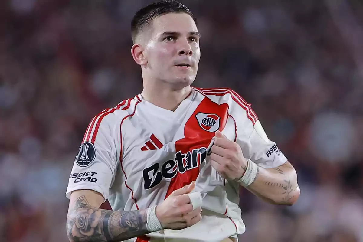 Futbolista con uniforme de River Plate celebrando en la cancha mientras sostiene la camiseta Futbolista con uniforme de River Plate celebrando en la cancha mientras sostiene la camiseta