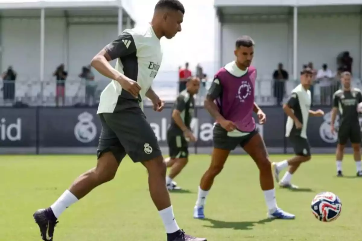 Soccer players training on a grass field with a ball while other players watch in the background Soccer players training on a grass field with a ball while other players watch in the background