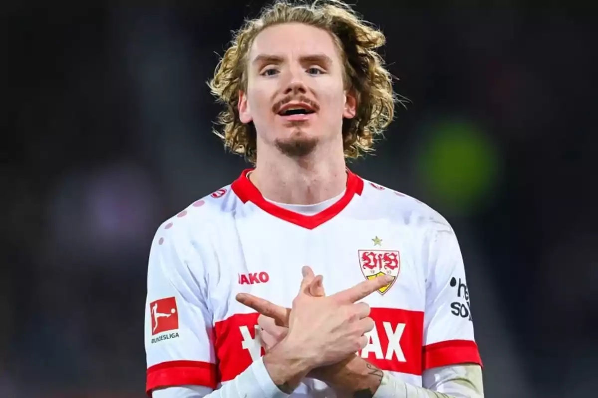 Soccer player in a white and red Stuttgart uniform celebrating with his arms crossed in front of his chest Soccer player in a white and red Stuttgart uniform celebrating with his arms crossed in front of his chest