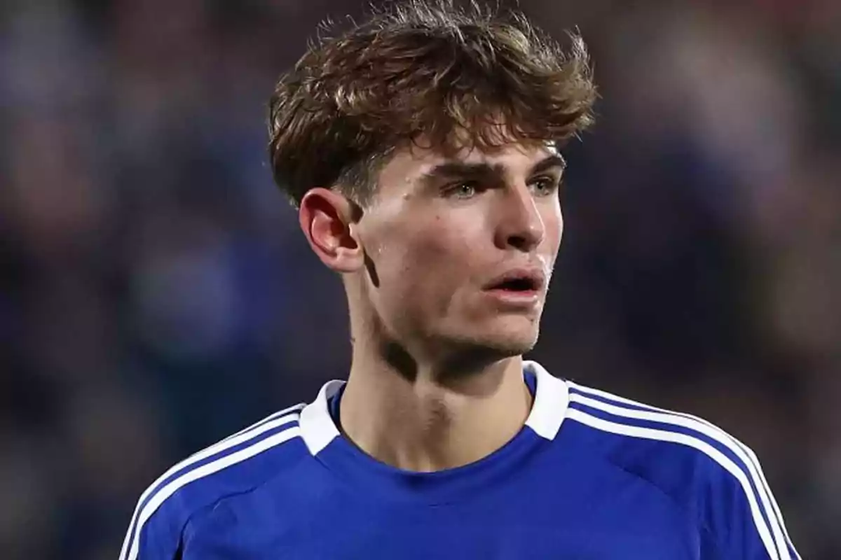 Young player wearing a blue and white jersey looking to the side in a stadium