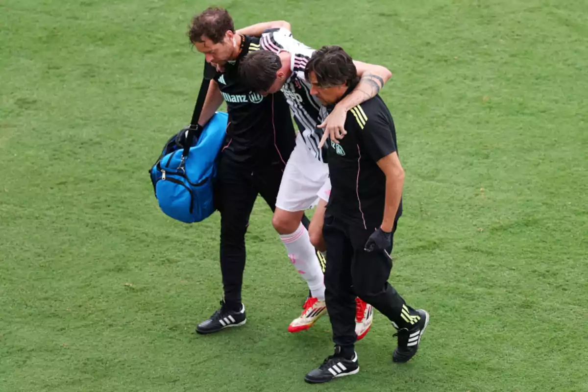 Un futbolista lesionado es ayudado a salir del campo por dos miembros del cuerpo médico durante un partido Un futbolista lesionado es ayudado a salir del campo por dos miembros del cuerpo médico durante un partido