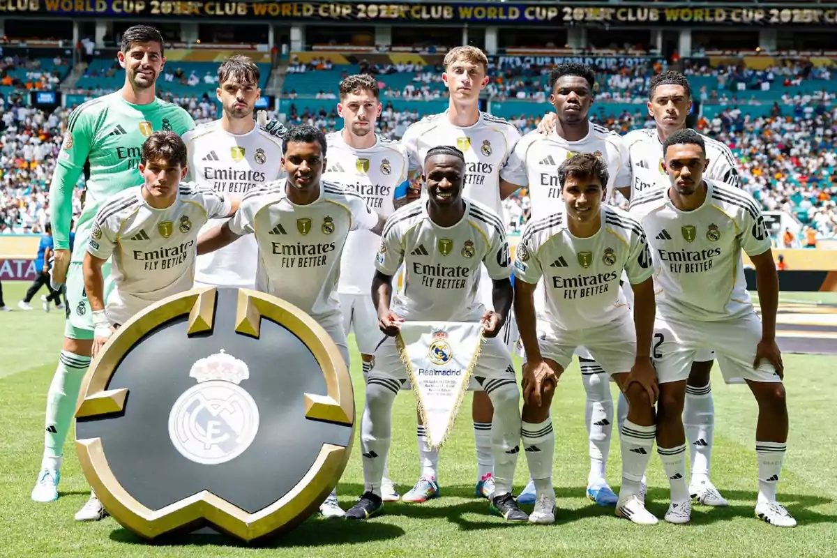 Eleven Real Madrid players pose on the field before a match, all wearing white uniforms with a large club crest on the front.