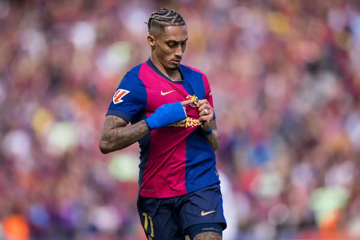 Futbolista con uniforme azul y rojo sostiene el escudo de su camiseta durante un partido Futbolista con uniforme azul y rojo sostiene el escudo de su camiseta durante un partido