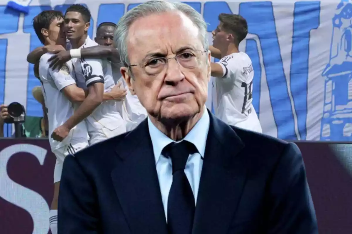 Hombre de traje con expresión seria en primer plano y jugadores de fútbol celebrando en el fondo
