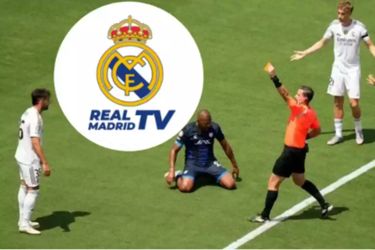A referee shows a yellow card to a player while other footballers watch and the Real Madrid TV logo appears in the background.