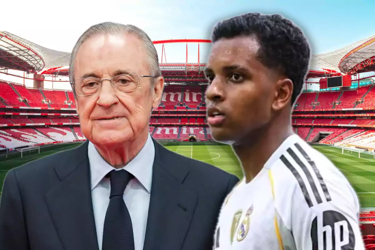 Two people in the foreground, one in a suit and the other in a white soccer uniform, pose in front of an empty soccer stadium with red stands.