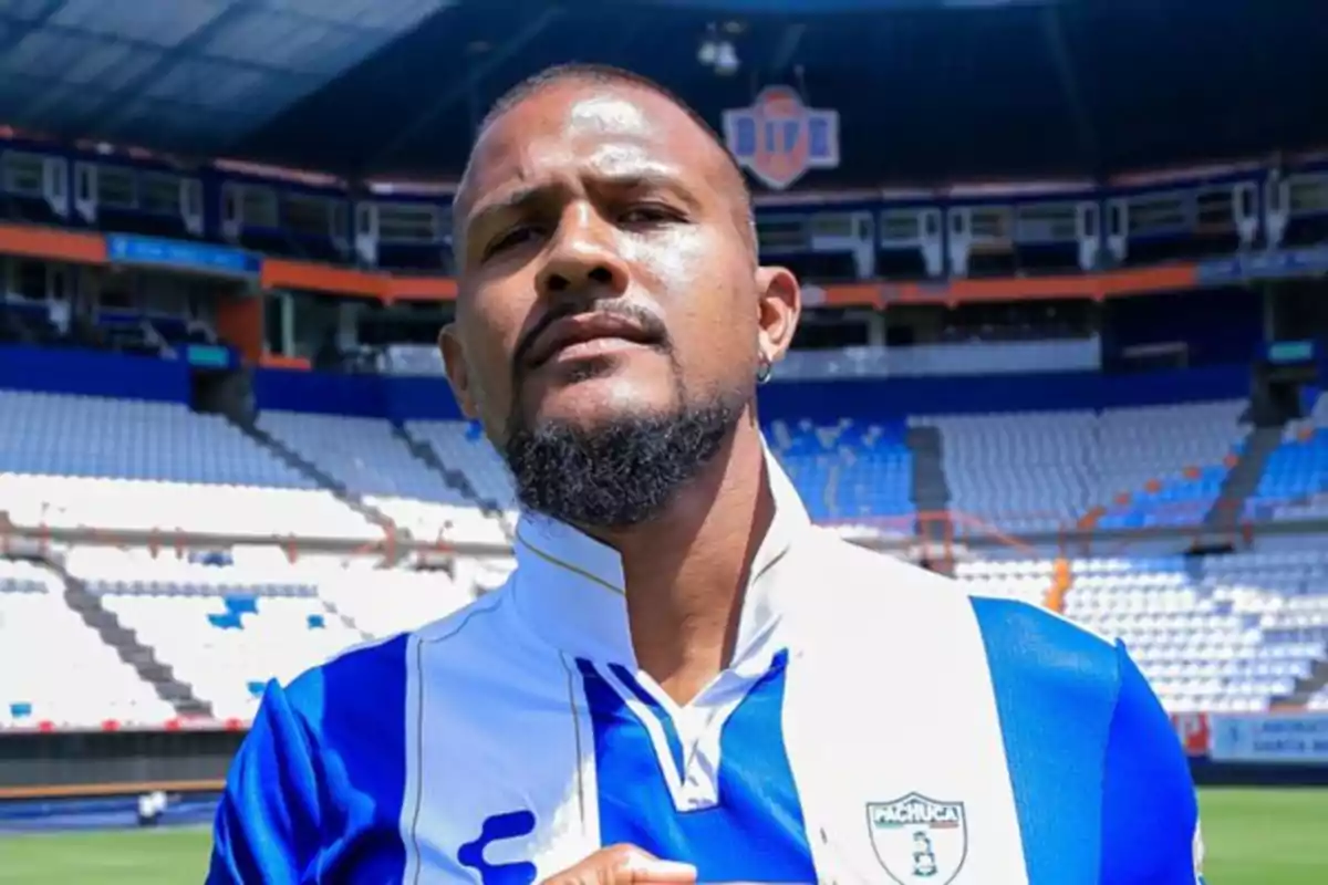 Futbolista con barba y camiseta de Pachuca posando en un estadio vacío