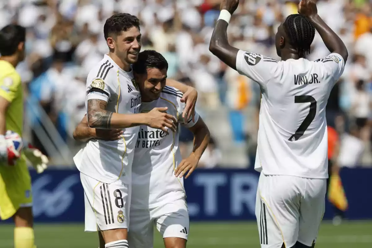 Real Madrid players celebrate a goal during a soccer match, hugging and smiling on the field. Real Madrid players celebrate a goal during a soccer match, hugging and smiling on the field.