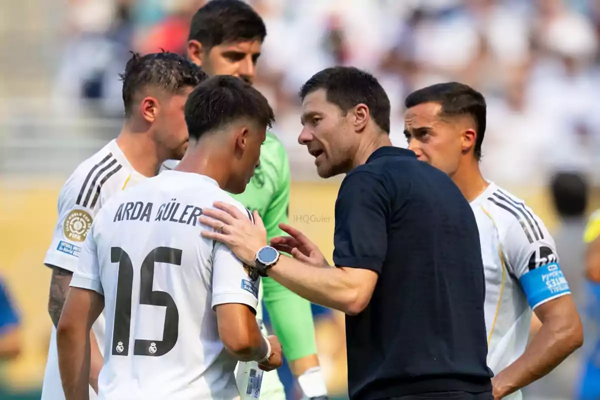 A soccer coach gives instructions to his players during a game while one of them holds a water bottle. A soccer coach gives instructions to his players during a game while one of them holds a water bottle.