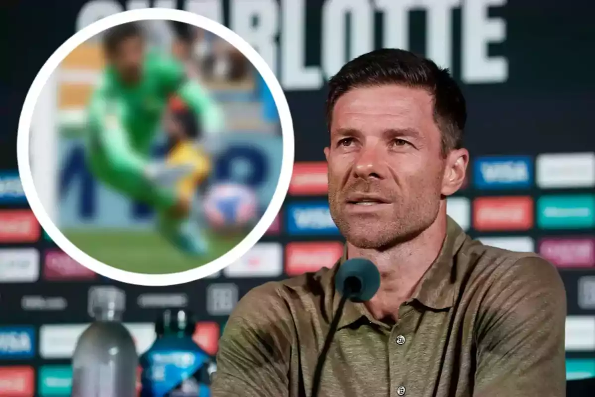 Hombre hablando en una conferencia de prensa con fondo de logotipos y una imagen borrosa de un portero de fútbol en la esquina superior izquierda