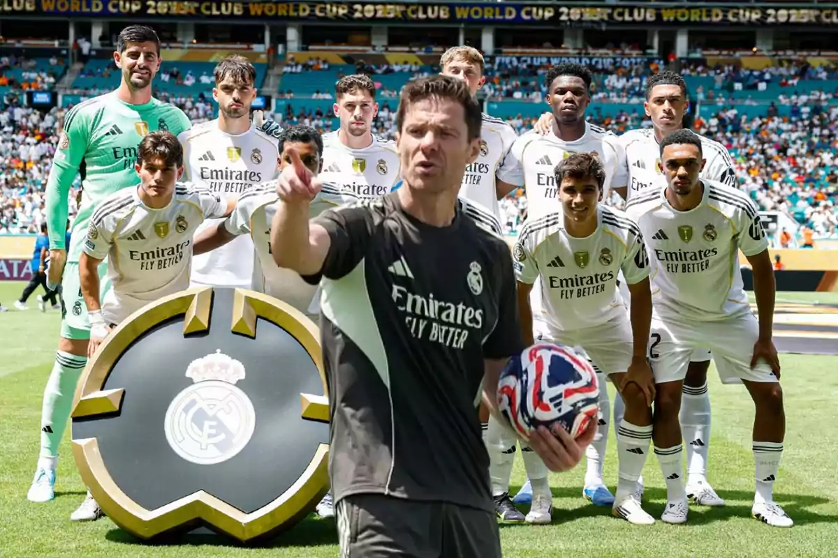 A group of Real Madrid players pose on the field before a match while a person in the team uniform holds a ball and points forward.